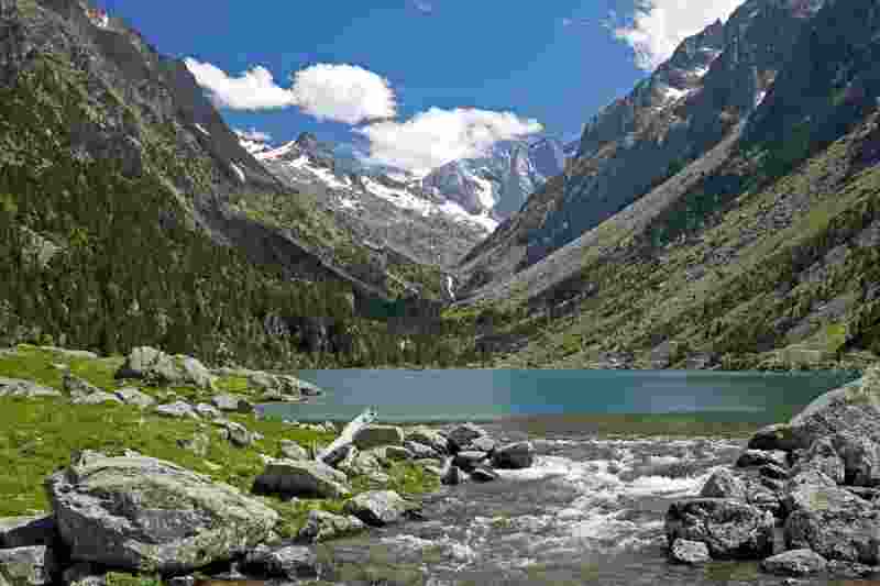 Green lake with green trees and mountains in the background. Lac st Guérin in France