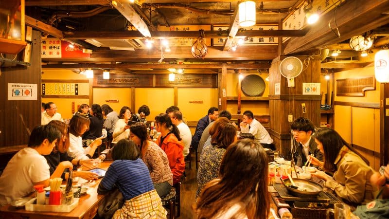 people sat down eating at a busy restaurant in tokyo